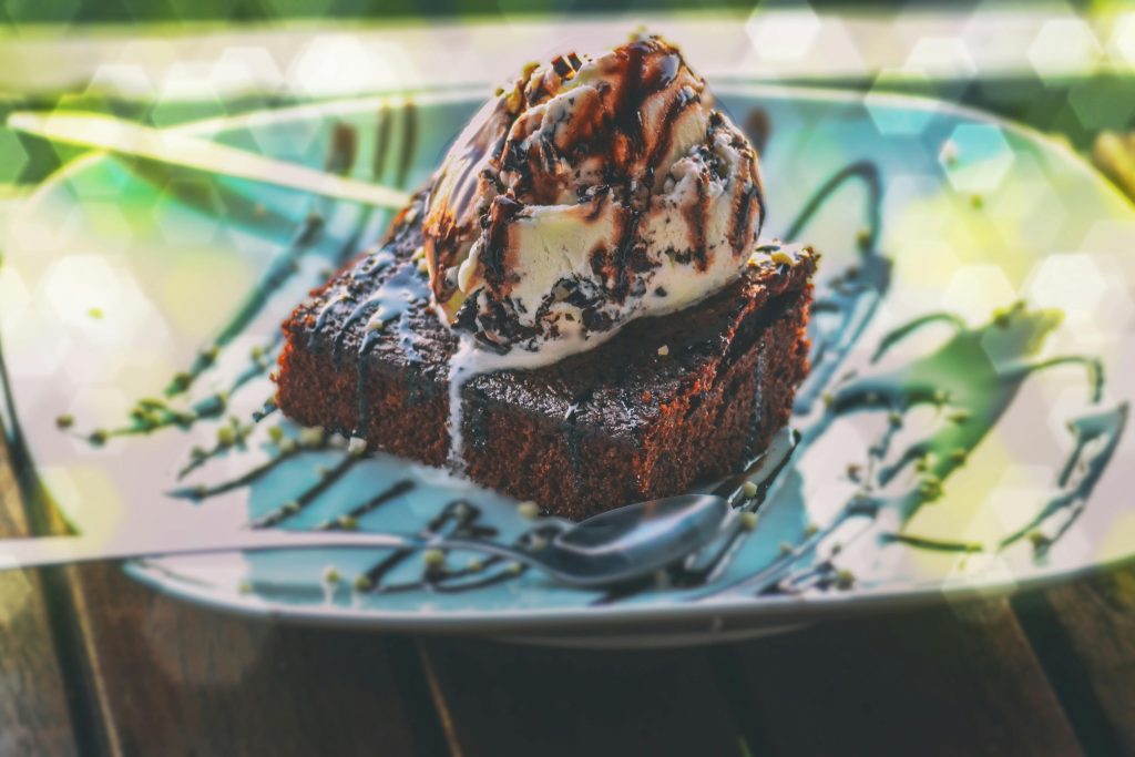 Close-up of a delicious chocolate brownie topped with vanilla ice cream on a plate.
